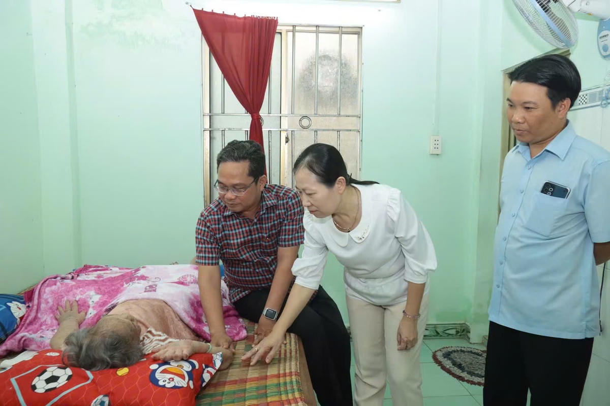 Ông Phạm Minh Tuấn (bìa trái) thăm, tặng quà Mẹ Việt Nam Anh hùng Nguyễn Thị Định. Ảnh: NN.