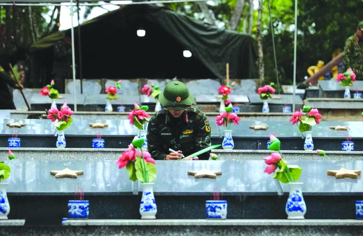 Thực hiện quy trình lưu trữ thông tin các phần mộ liệt sỹ trước khi khai quật lấy mẫu giám định ADN. Ảnh: TTXVN