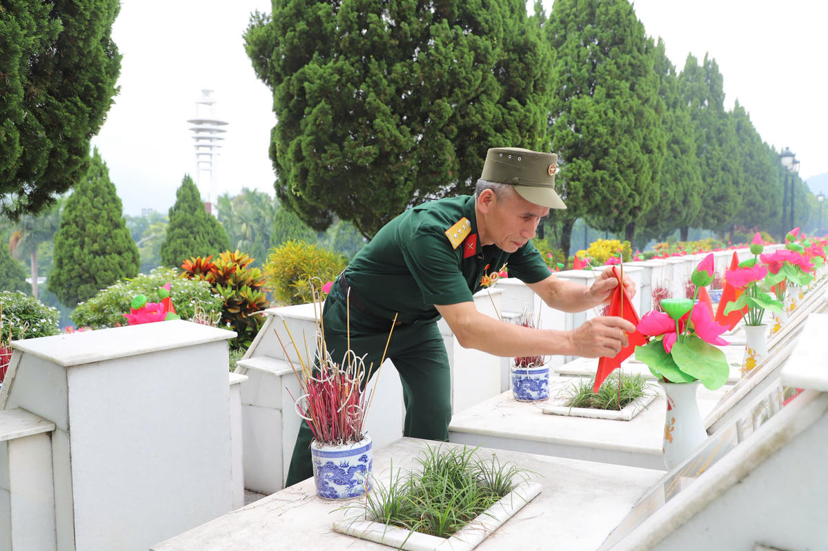 Cựu chiến binh Bùi Huy Nam trở lại Nghĩa trang Liệt sĩ Quốc gia Vị Xuyên, cẩn thận chỉnh lại lá cờ Tổ quốc trên phần mộ đồng đội như một lời tri ân sâu nặng sau nhiều năm chiến tranh đã lùi xa.