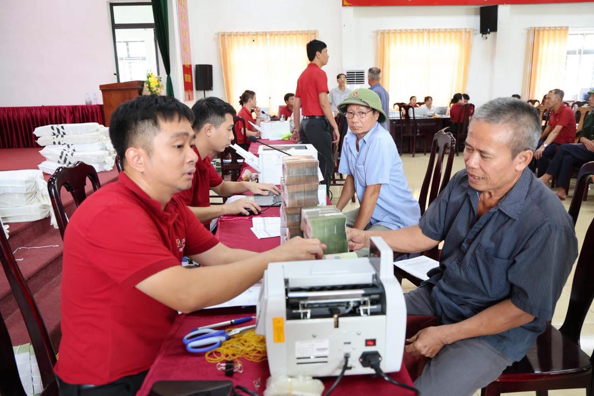 Người dân phấn khởi nhận tiền đền bù. Ảnh: T.H