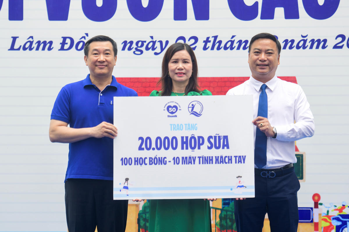 Đại diện Quỹ sữa Vươn cao Việt Nam, ông Đỗ Thanh Tuấn - Giám đốc Đối ngoại Vinamilk (bên trái) và ông Đinh Tiến Hải - Giám đốc Quỹ Bảo trợ Trẻ em Việt Nam - trao bảng tượng trưng các phần quà thiết thực cho đại diện Trường Tiểu học An Hiệp, xã Hiệp Thạnh (Ảnh: Hải An).
