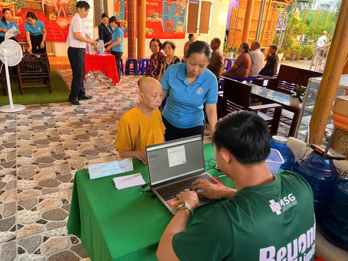 Bà Trần Thị Kim Thảo - Phó Trưởng Phòng Tuyên truyền và Hỗ trợ người tham gia, BHXH thành phố hướng dẫn, hỗ trợ người dân thăm khám mắt. Ảnh: Quỳnh Anh