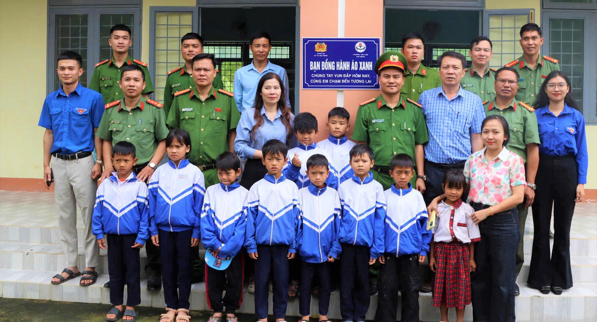 Lãnh đạo, Công an xã Tu Mơ Rông cùng thầy cô giáo, học sinh của Trường Tiểu học Kim Đồng gắn biển chương trình “Bạn đồng hành áo xanh”. Ảnh: TM.