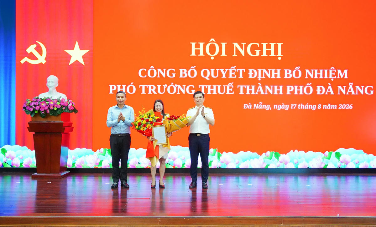 Phó Cục trưởng Cục Thuế Vũ Chí Hùng (bên phải)  trao quyết định bổ nhiệm, tặng hoa chúc mừng bà Trần Thị Dung. Ảnh: MQ.