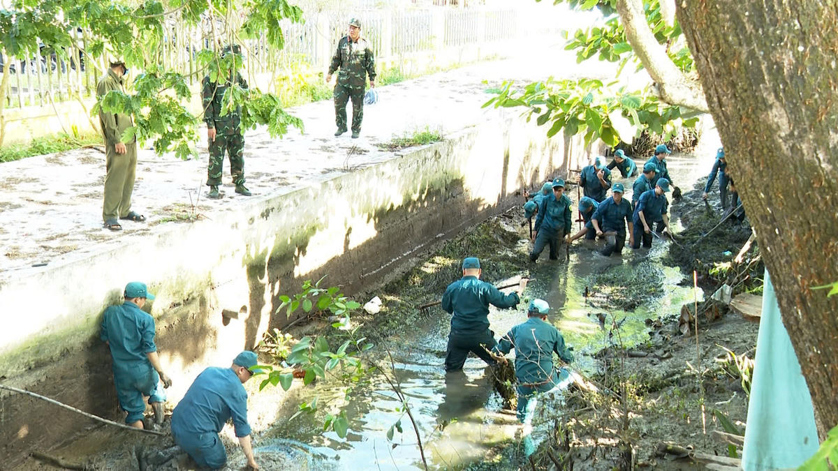 Lực lượng Bộ đội Biên phòng và đoàn viên, thanh niên phát quang, thu gom cây cỏ, làm sạch tuyến kênh nội đồng. (Ảnh: Trần Giỏi).
