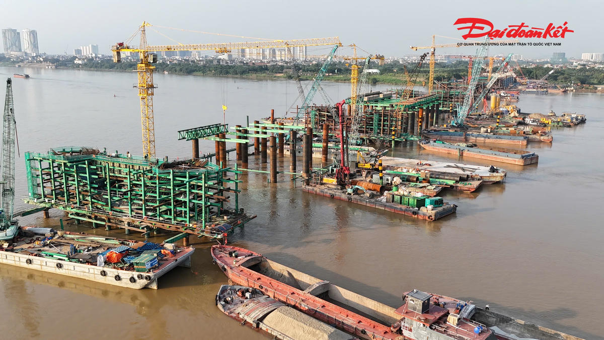 Công nhân và máy móc hoạt động liên tục, nhiều mũi thi công được triển khai đồng thời trên bờ và dưới sông.
