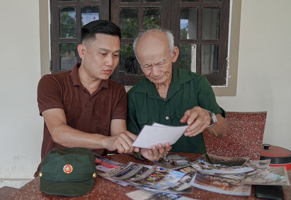 Ông Lê Văn Phước xem lại những hình ảnh và tư liệu trong quá trình trò chuyện về những năm tháng quân ngũ.