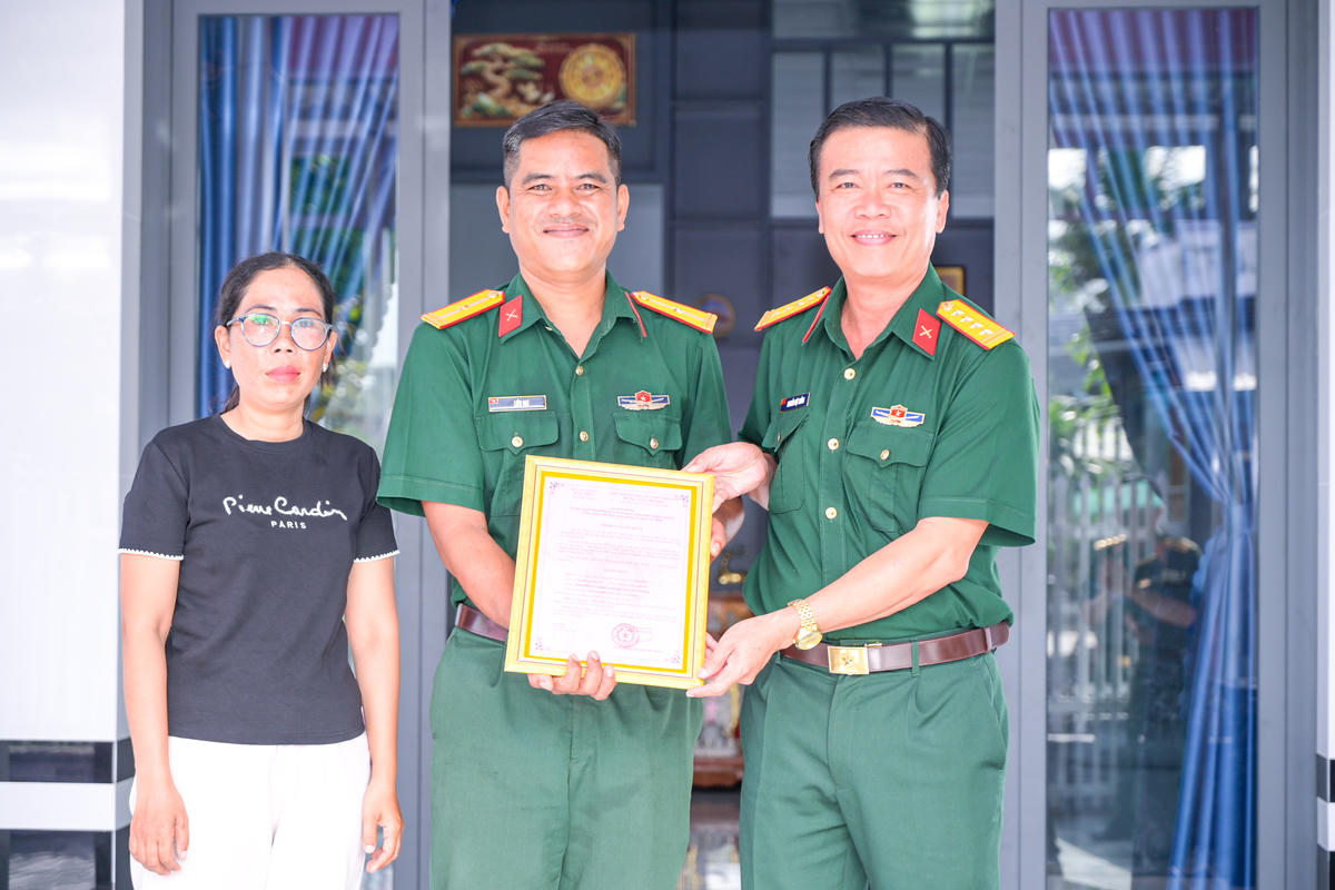 Đại tá Nguyễn Việt Thắng - Chính ủy Bộ CHQS tỉnh An Giang trao quyết định bàn giao nhà đồng đội cho gia đình Thiếu tá QNCN Liêu Đạt. Ảnh: Phương Vũ