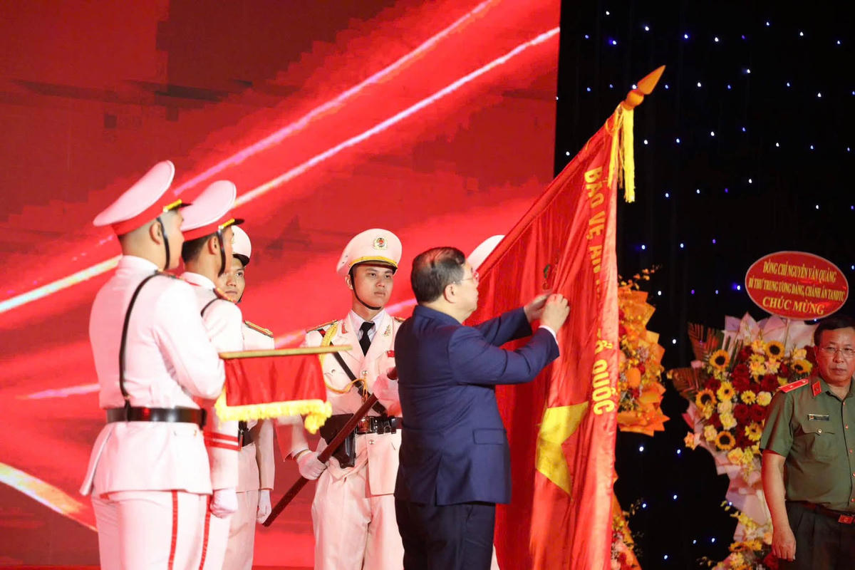 Phó Thủ tướng Thường trực Chính phủ Phạm Gia Túc gắn huy hiệu Anh hùng Lực lượng vũ trang nhân dân lên Cờ truyền thống của Công an TP  Đà Nẵng. Ảnh: CĐ.