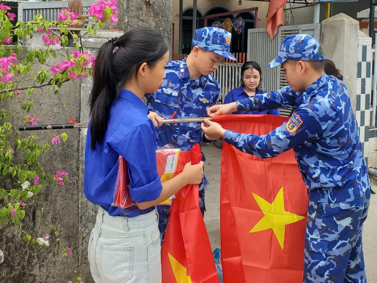 Chiến sĩ Hải đoàn 21 cùng đoàn viên, thanh niên xã Núi Thành treo cờ Tổ quốc. Ảnh: CS.