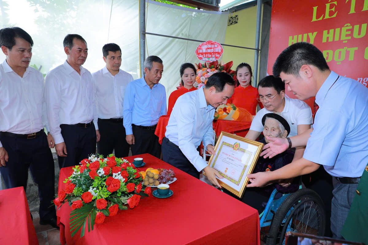 Trưởng ban Tuyên giáo Trung ương Trịnh Văn Quyết trao huy hiệu 80 năm tuổi Đảng cho bà Lê Thị Thủy. Ảnh: Minh Hiếu