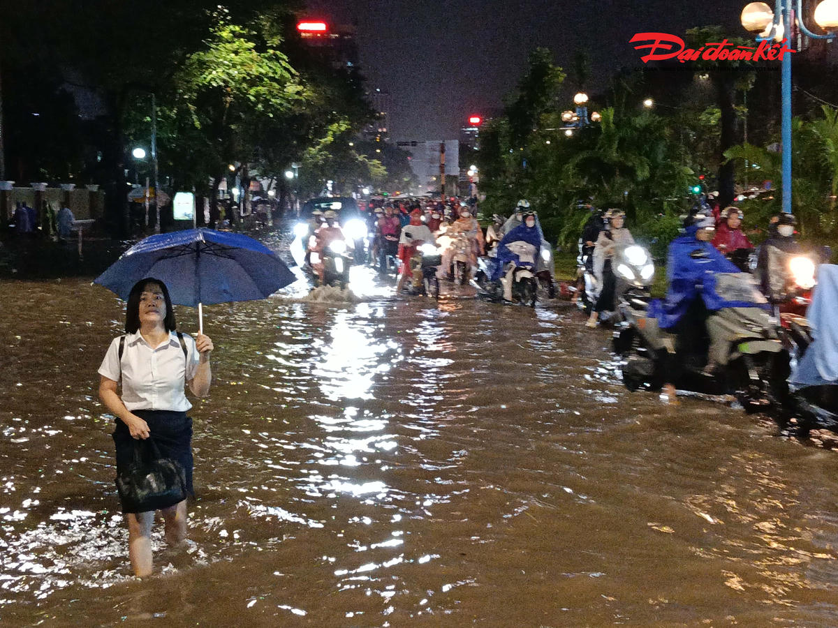 Tại một số khu vực, nước mưa chưa kịp thoát đã tràn ra mặt đường, tạo thành những đoạn dềnh nước. Người đi xe máy phải giảm tốc độ, nối đuôi nhau di chuyển qua các vị trí nước sâu, trong khi ô tô cũng phải đi chậm để tránh gây sóng nước.