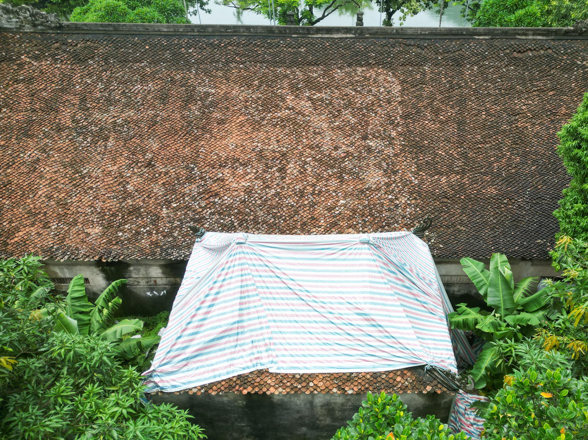 Để xử lý tạm thời việc thấm dột tại đình, chính quyền xã Tống Sơn cho phủ bạt để che các lỗ thủng trên mái ngói. Ảnh: Đình Minh
