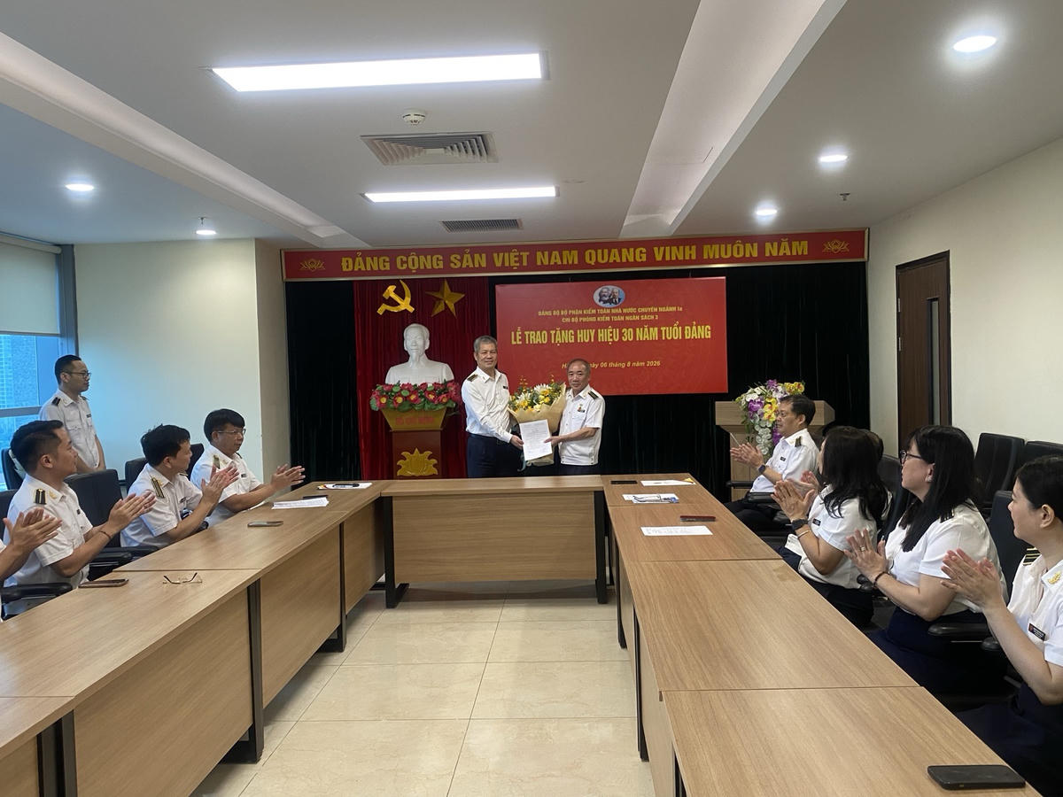 Ông Phạm Văn Học - Bí thư Đảng ủy bộ phận, Kiểm toán trưởng KTNN chuyên ngành Ia trao Quyết định và tặng hoa chúc mừng ông Đoàn Thanh Long được nhận Huy hiệu 30 năm tuổi Đảng. Ảnh: CTV