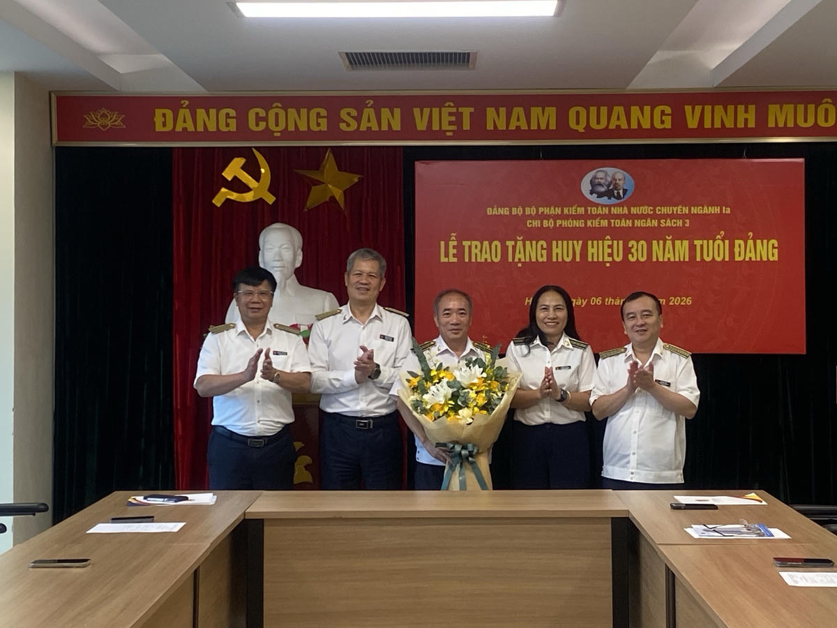 Lãnh đạo Đảng ủy bộ phận KTNN chuyên ngành Ia và các đại biểu tặng hoa chúc mừng đảng viên Đoàn Thanh Long được trao Huy hiệu 30 năm tuổi Đảng. Ảnh: CTV