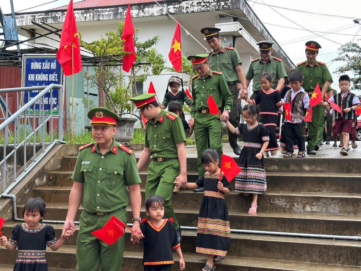 Chiến sĩ Công an xã  dẫn học sinh Trường PTDTBT Tiểu học Tu Mơ Rông vào dự lễ khai giảng. Ảnh: CV.
