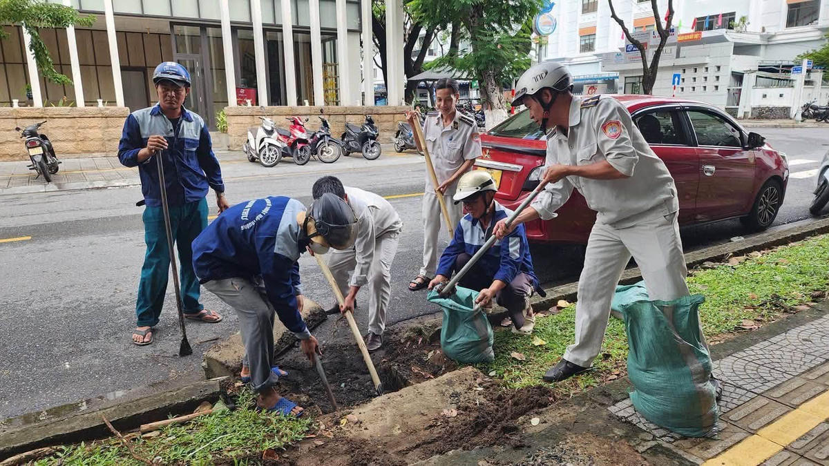 Thu gom rác thải, đất đá tại các miệng thu nước tại phường Hải Châu. Ảnh: Nguyễn Tú. 