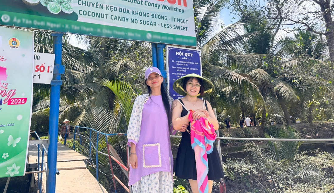 Du khách chụp ảnh lưu niệm tại điểm tham quan, trải nghiệm sản phẩm kẹo dừa. (Ảnh: Thanh Lâm).