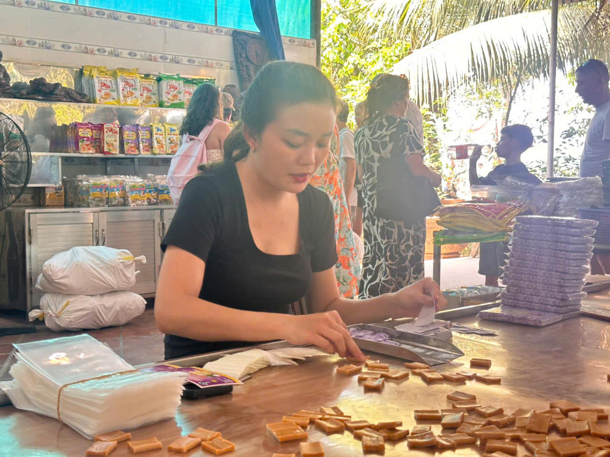 Công đoạn chế biến, đóng gói những miếng kẹo dừa tại cơ sở sản xuất. (Ảnh: Thanh Lâm).