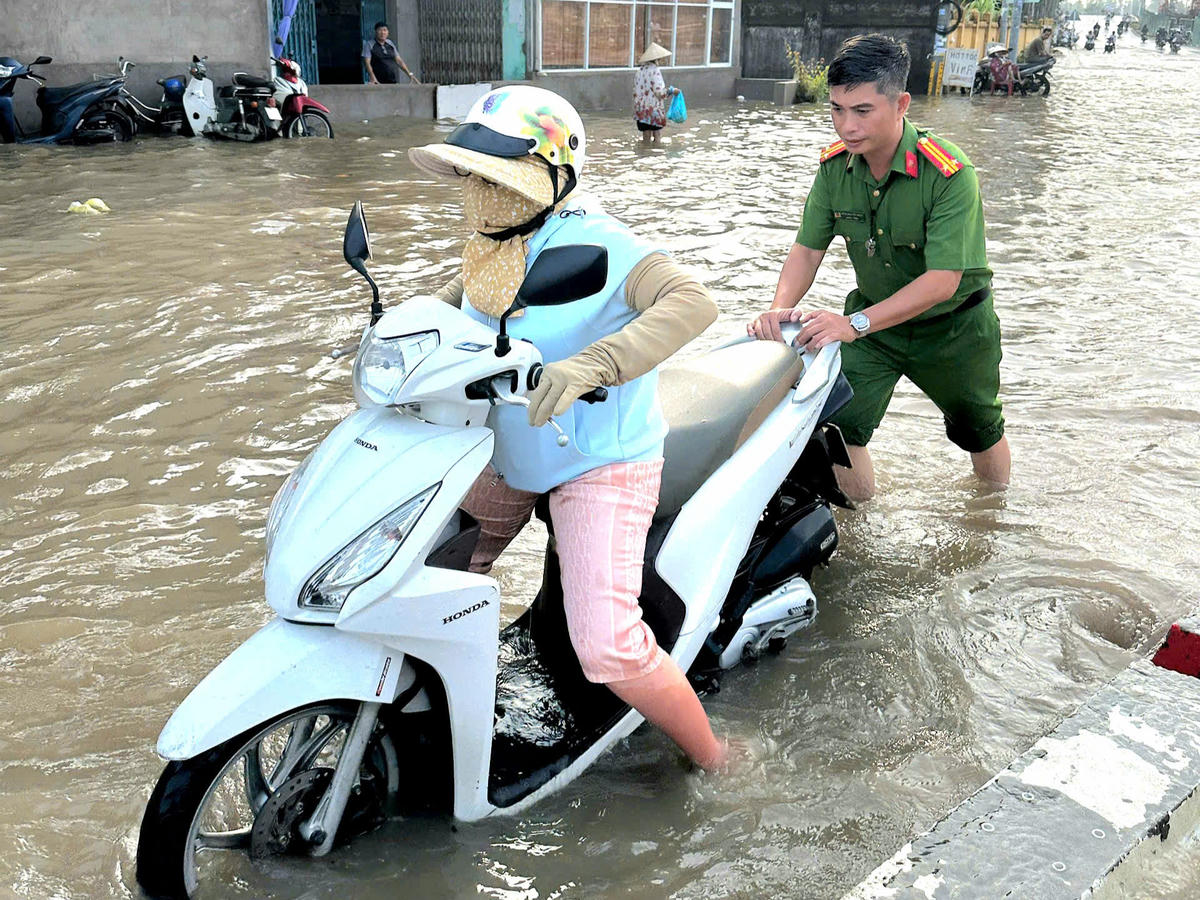 Công an địa phương hỗ trợ người dân qua vùng ngập sâu. Ảnh TP