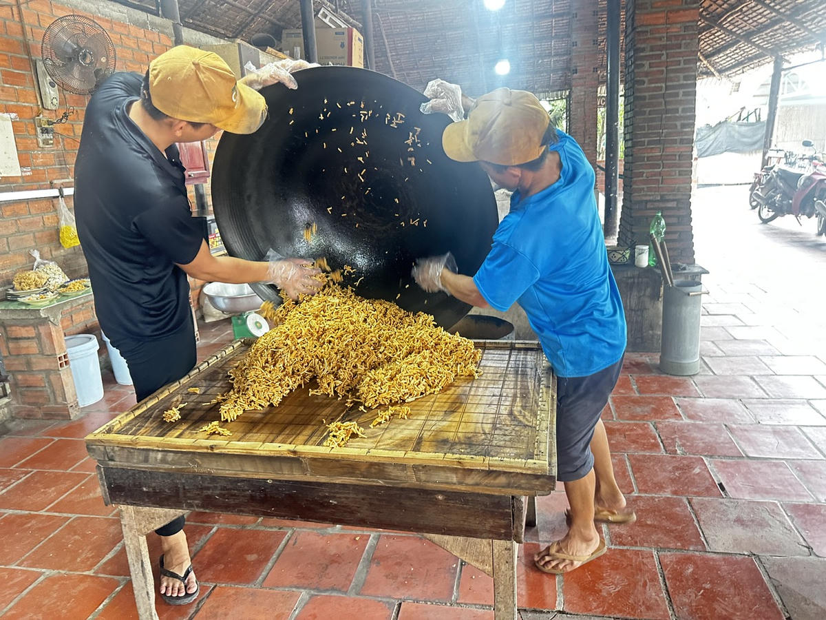 Những mẻ bánh cốm nóng hổi được chế biến theo phương pháp truyền thống, bảo đảm chất lượng trước khi đóng gói. (Ảnh: Thanh Lâm).