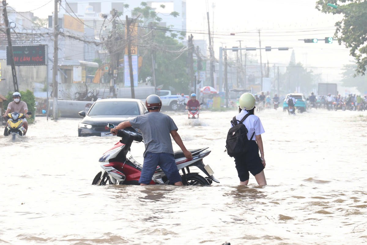 Nước ngập khiến nhiều xe máy chết máy, người dân phải dắt bộ qua các đoạn đường ngập. 