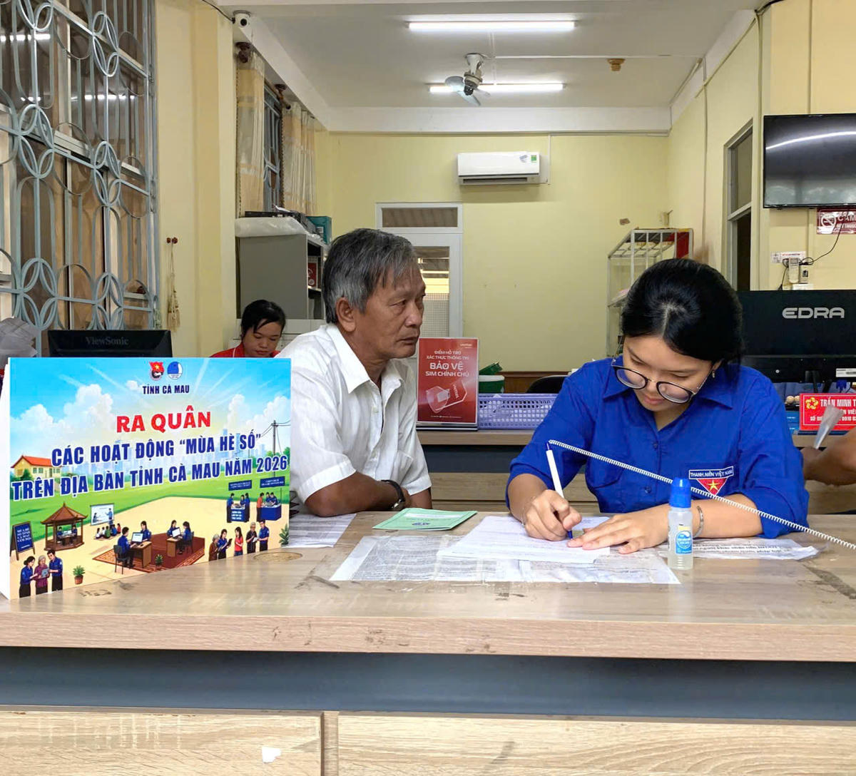 Đoàn viên hỗ trợ người dân tích hợp, sử dụng Sổ sức khỏe điện tử. Ảnh: Nguyên Du