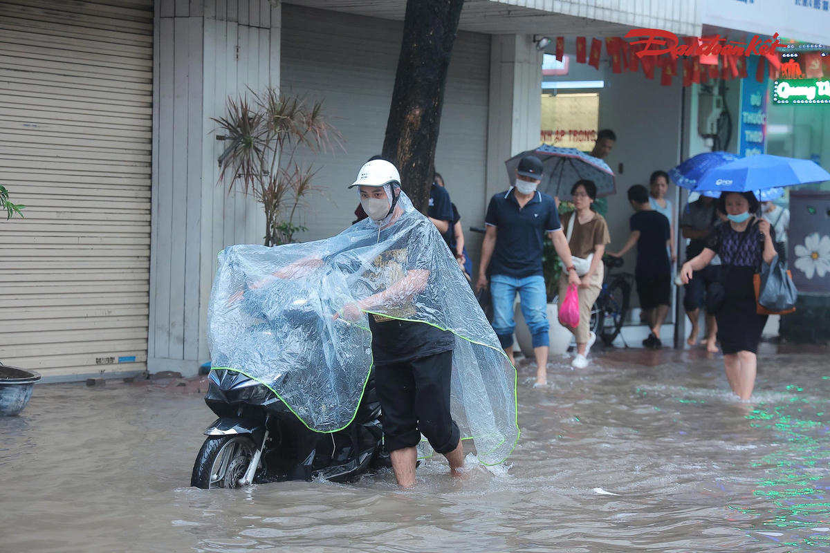 Nước ngập khiến nhiều xe chết máy giữa đường. Nhiều người dân phải dắt xe qua khu vực ngập, việc di chuyển gặp nhiều khó khăn.