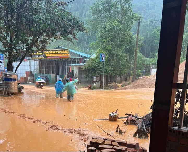 Bùn đất ngập đến đầu gối, người dân xã Quan Sơn vất vả đi qua khu vực bị sạt lở. Ảnh: DVC Quan Sơn
