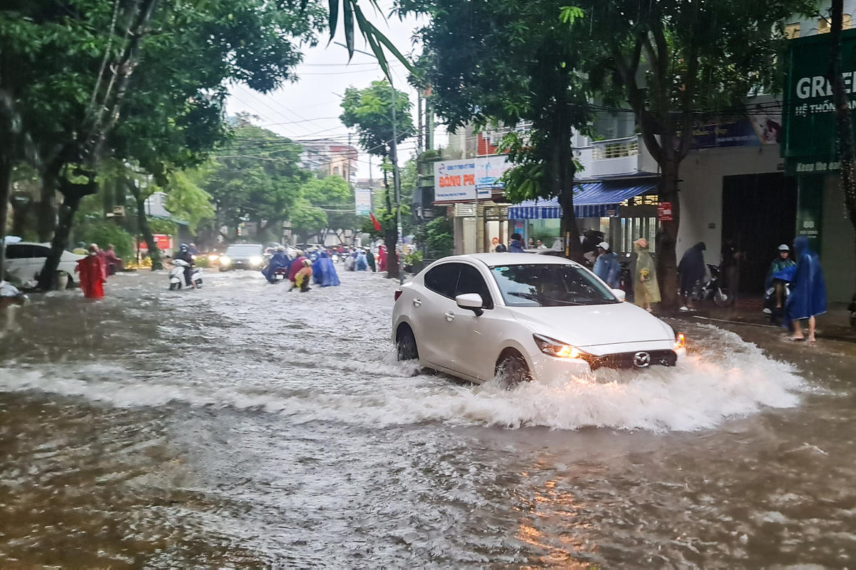 Xe ô tô trên đường Đội Cung cố gắng vượt qua khu vực bị ngập. Ảnh: Anh Tuấn