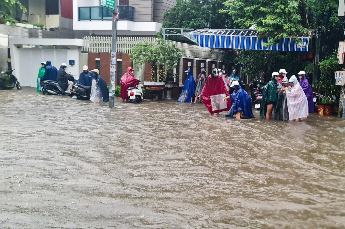 Người đi xe máy bì bõm lội nước, kéo xe vào lề để tránh chết máy. Ảnh: Anh Tuấn