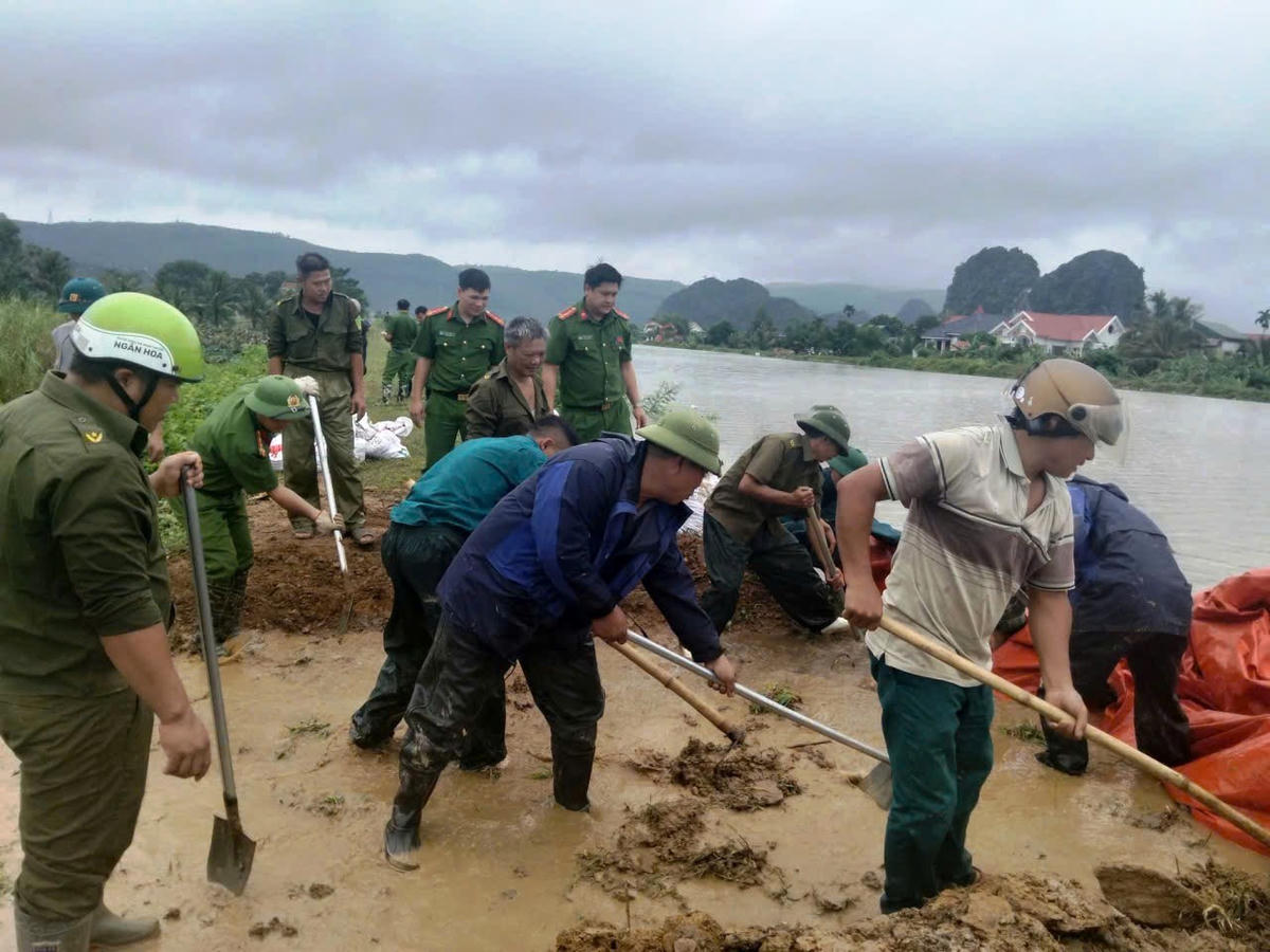 Lực lượng công an, quân sự địa phương phối hợp cùng người dân gia cố các tuyến đê bị nước lũ tràn qua.