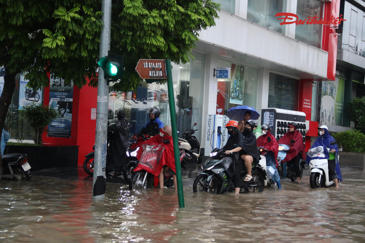 Người dân len lỏi tìm những vị trí ít ngập để di chuyển qua khu vực nước dâng cao.