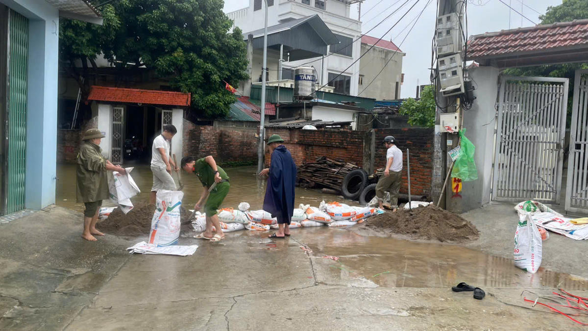 Các lực lượng chức năng cùng người dân ngăn lũ tràn vào khu dân cư.