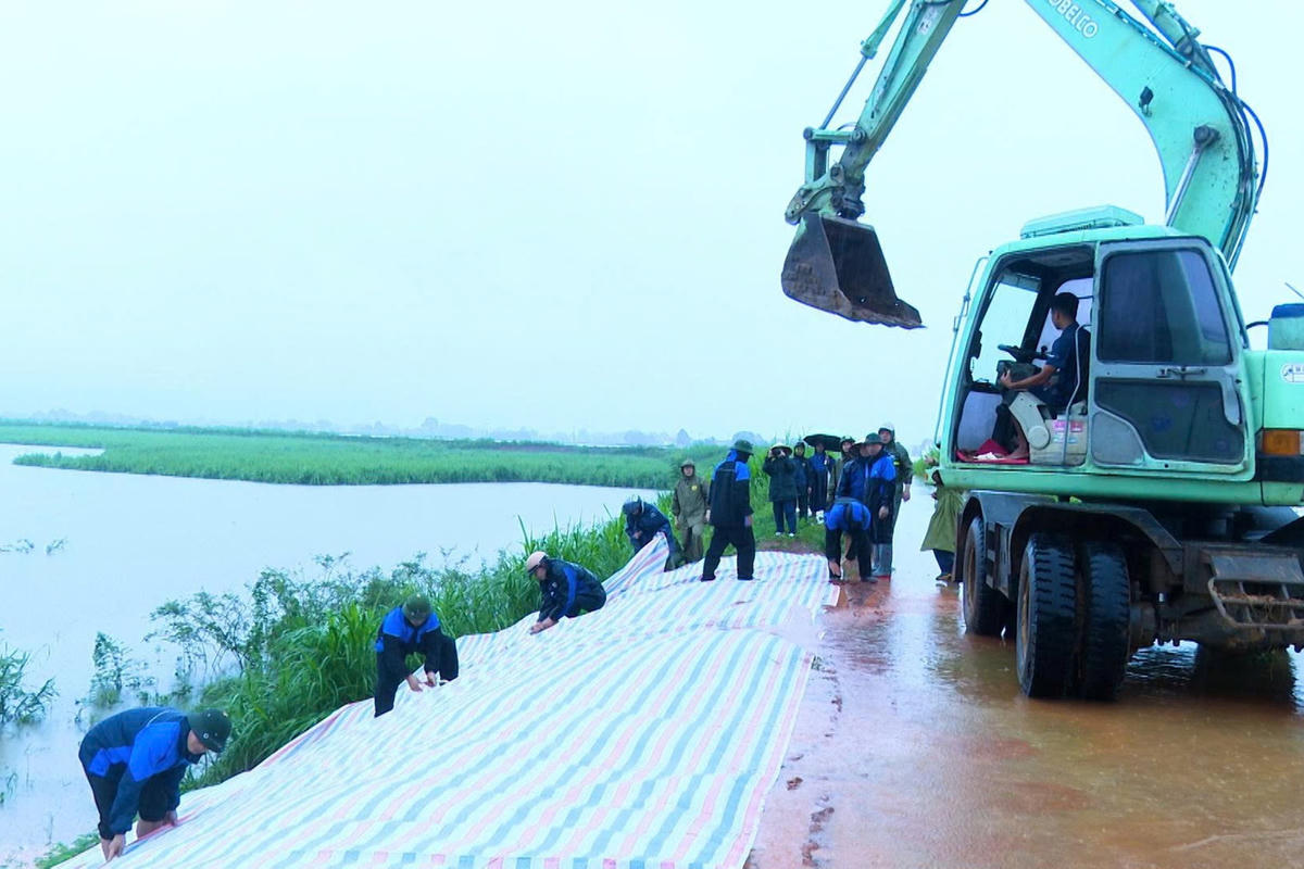 Lực lượng chức năng xử lý sự cố sạt lở trên đê hữu sông Cầu Chày. Ảnh: DVC Xuân Tín