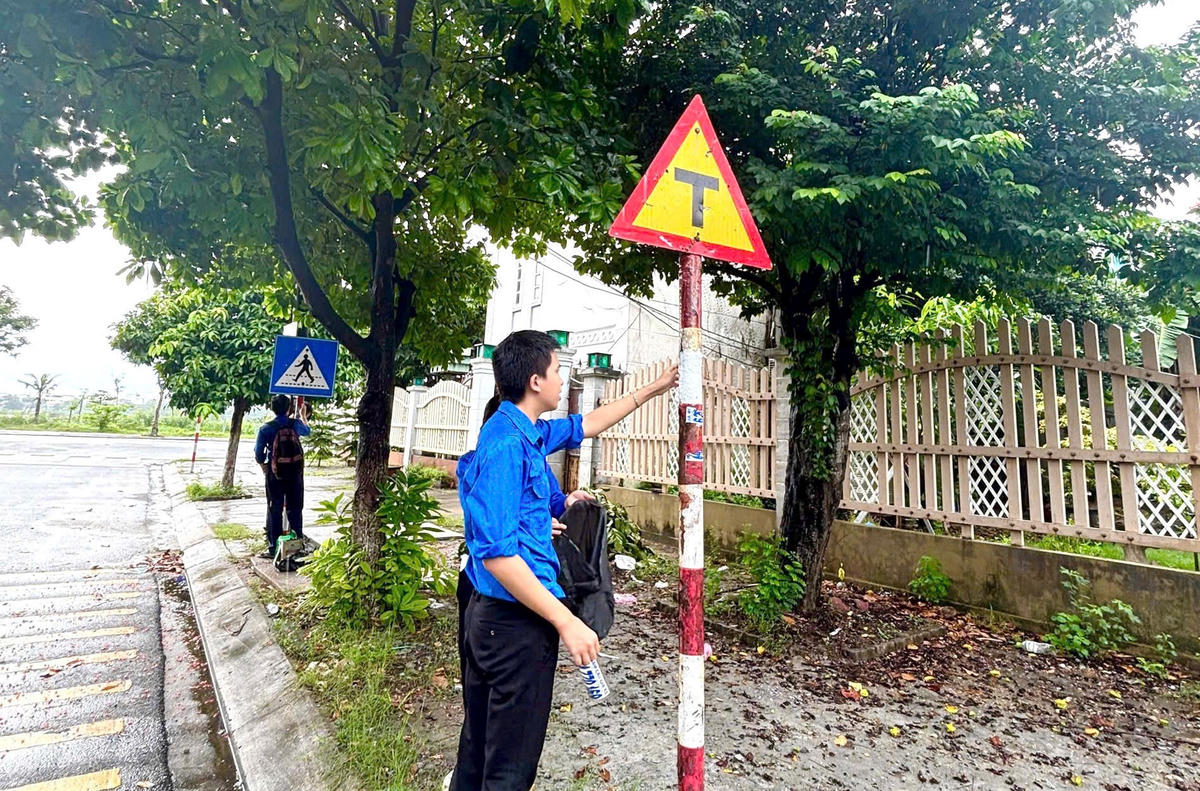 Đoàn viên, thanh niên TP Đà Nẵng gỡ biển dán quảng cáo tại biển báo hiệu. Ảnh: TĐ.