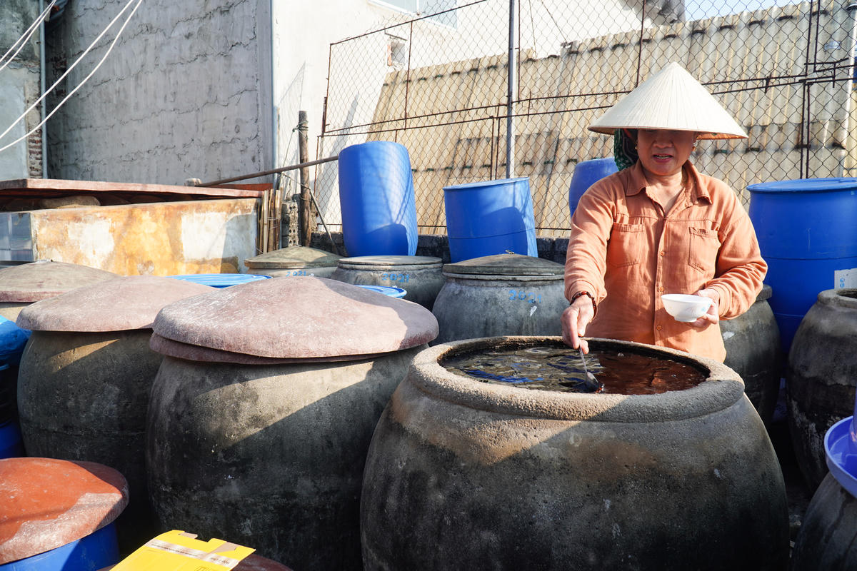 Sinh ra trong gia đình có nhiều đời làm nước mắm, bà Nguyễn Thị Lài (61 tuổi, trú tổ dân phố Thượng Hải, phường Tĩnh Gia) sớm gắn bó với nghề chế biến thủy sản truyền thống. Những năm đầu, cơ sở của gia đình chủ yếu sản xuất với quy mô nhỏ, phục vụ nhu cầu tiêu dùng trong vùng. Ảnh: Đình Minh
