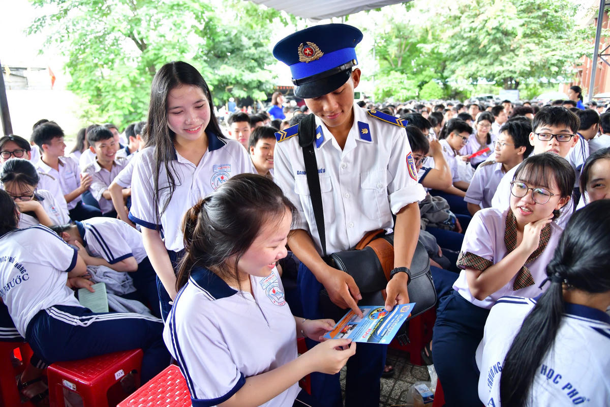 Cán bộ, chiến sĩ Cảnh sát biển phát tài liệu tuyên truyền cho học sinh. Ảnh: Hồng Vân.