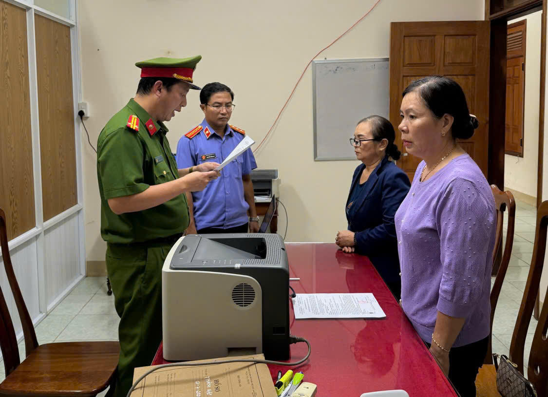Cơ quan điều tra đọc lệnh khởi tố bà Bùi Thị Phú (đeo kính) và Nguyễn Thị Mai. Ảnh: Văn Tài