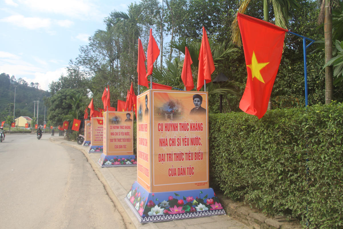 Cờ Tổ quốc, khẩu hiệu chào mừng kỷ niệm 150 năm Ngày sinh cụ Huỳnh Thúc Kháng. Ảnh: NT.
