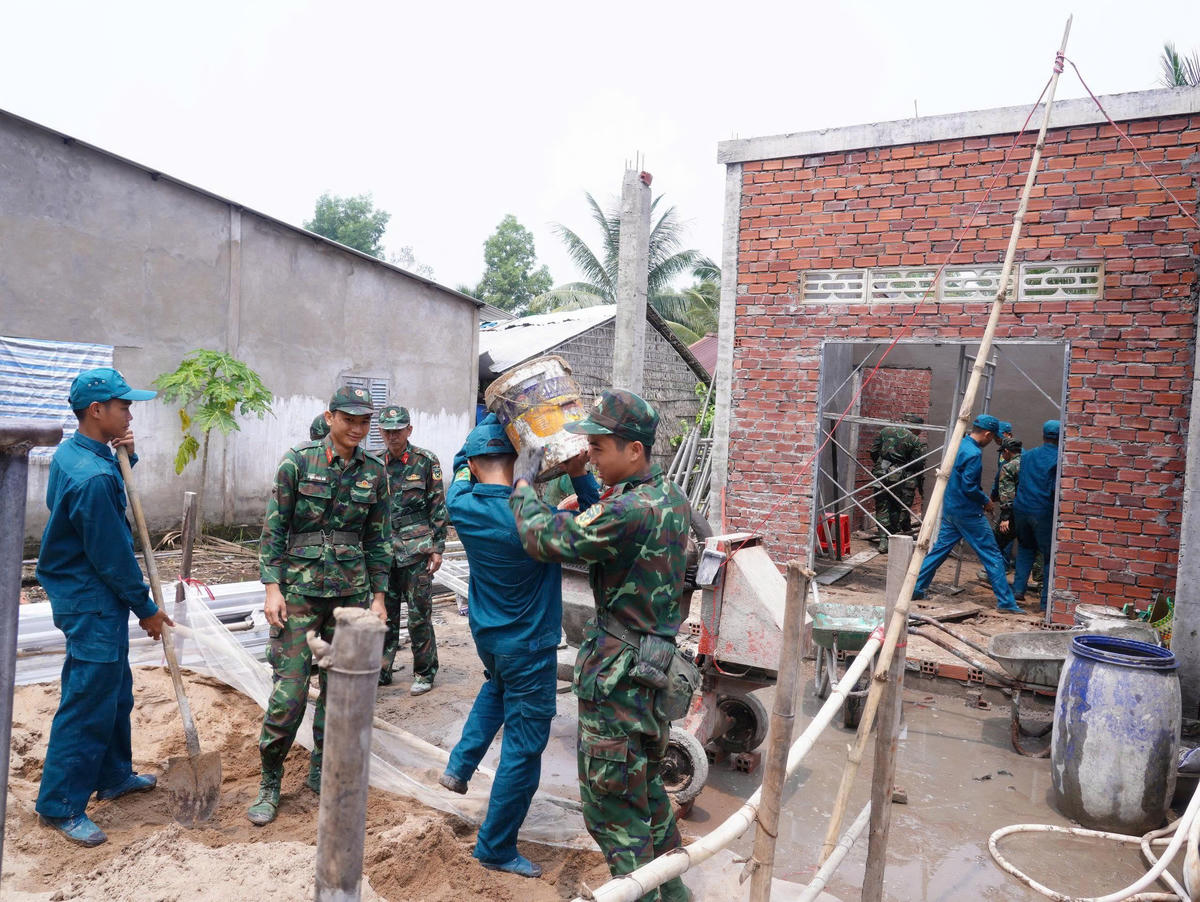 Các chiến sĩ, lực lượng dân quân tự vệ hỗ trợ trong công tác xây dựng. (Ảnh: D.H)