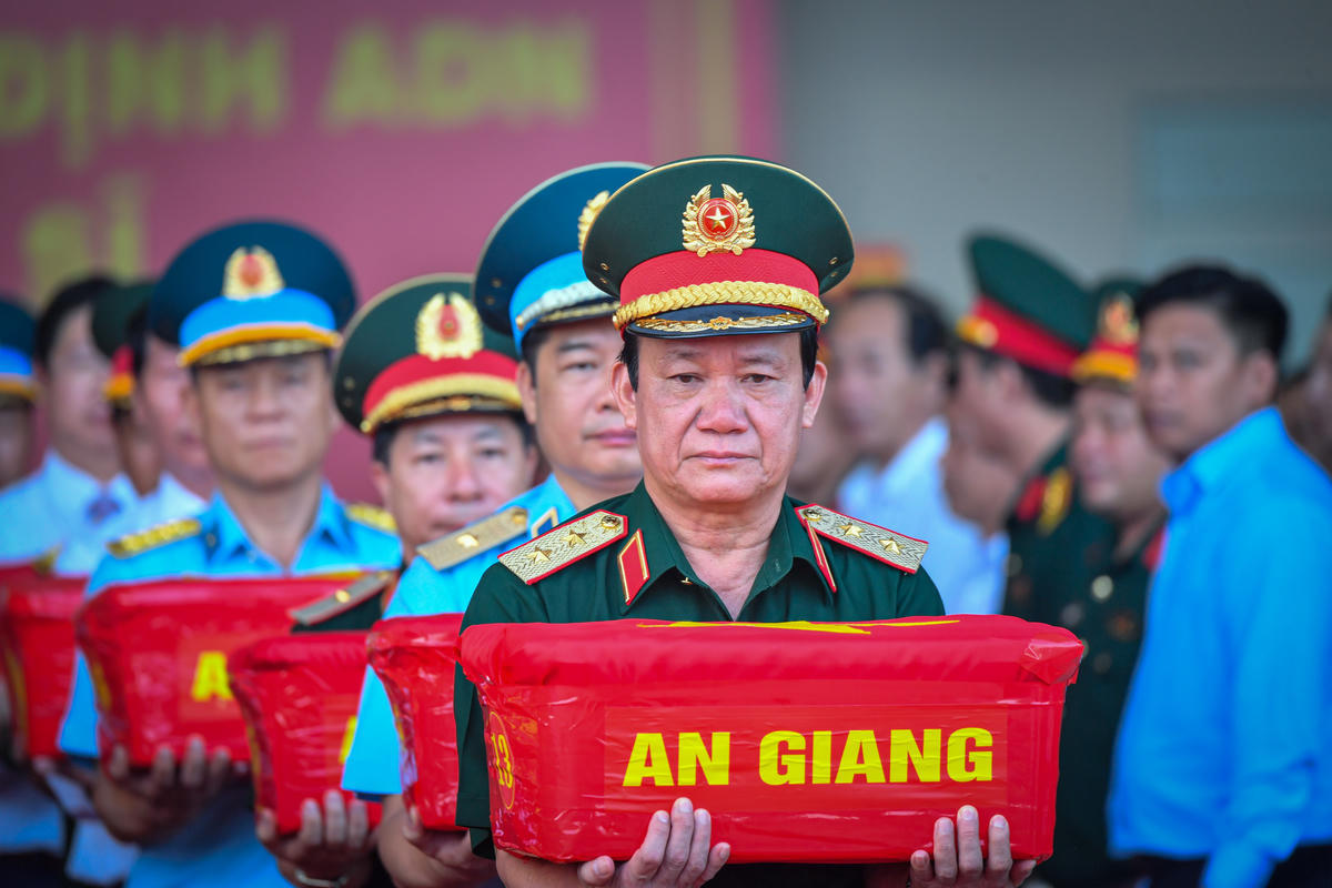 Trung tướng Hồ Văn Thái - Chính ủy Quân khu 9 trực tiếp nâng thùng mẫu hài cốt liệt sĩ trong nghi thức vận chuyển, bàn giao. Mỗi thùng mẫu được trao nhận trang trọng, chặt chẽ trước khi đưa lên máy bay. Ảnh: Phương Vũ