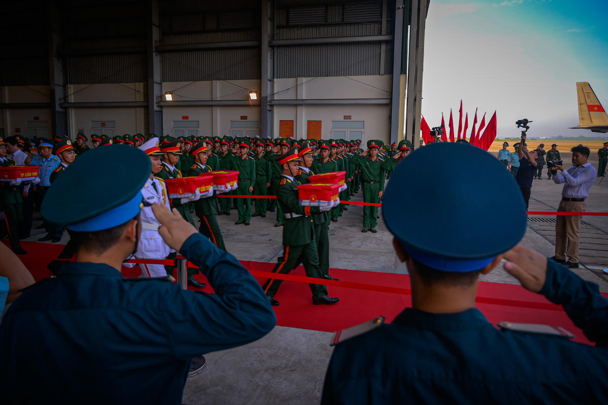 Cán bộ, chiến sĩ Không quân thực hiện nghi thức chào khi những thùng mẫu hài cốt liệt sĩ lần lượt được đưa lên máy bay. Ảnh: Phương Vũ
