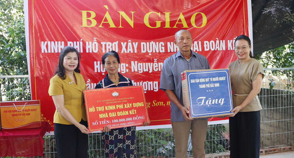 Bà Lâm Thị Hương Thành Phó Chủ tịch HĐND thành phố Bắc Ninh và bà Thái Hải Anh, Phó Chủ tịch Ủy ban MTTQ thành phố trao biển tượng trưng hỗ trợ kinh phí 100 triệu đồng xây dựng nhà Đại đoàn kết cho gia đình ông Nguyễn Văn Đào. Ảnh: V.Đức