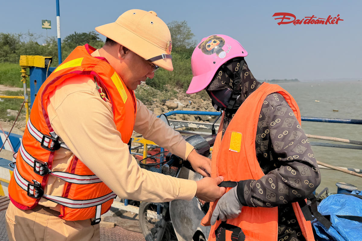 CSGT Hà Nội hướng dẫn người dân mặc áo phao, sử dụng dụng cụ cứu sinh đúng cách khi đi phà qua sông.