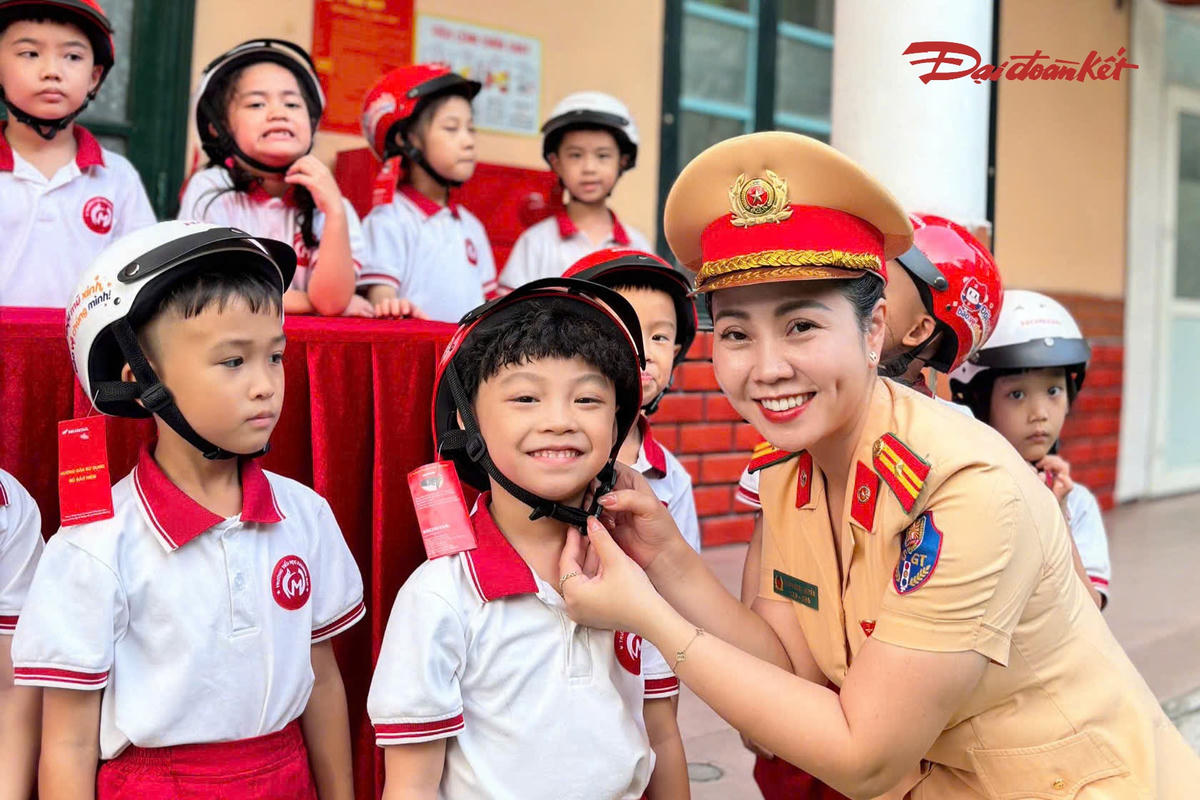 Thiếu tá Đoàn Ngọc Huyền, cán bộ Đội Tuyên truyền, Phòng CSGT Công an TP Hà Nội, hướng dẫn học sinh lớp 1 đội mũ bảo hiểm đúng cách.