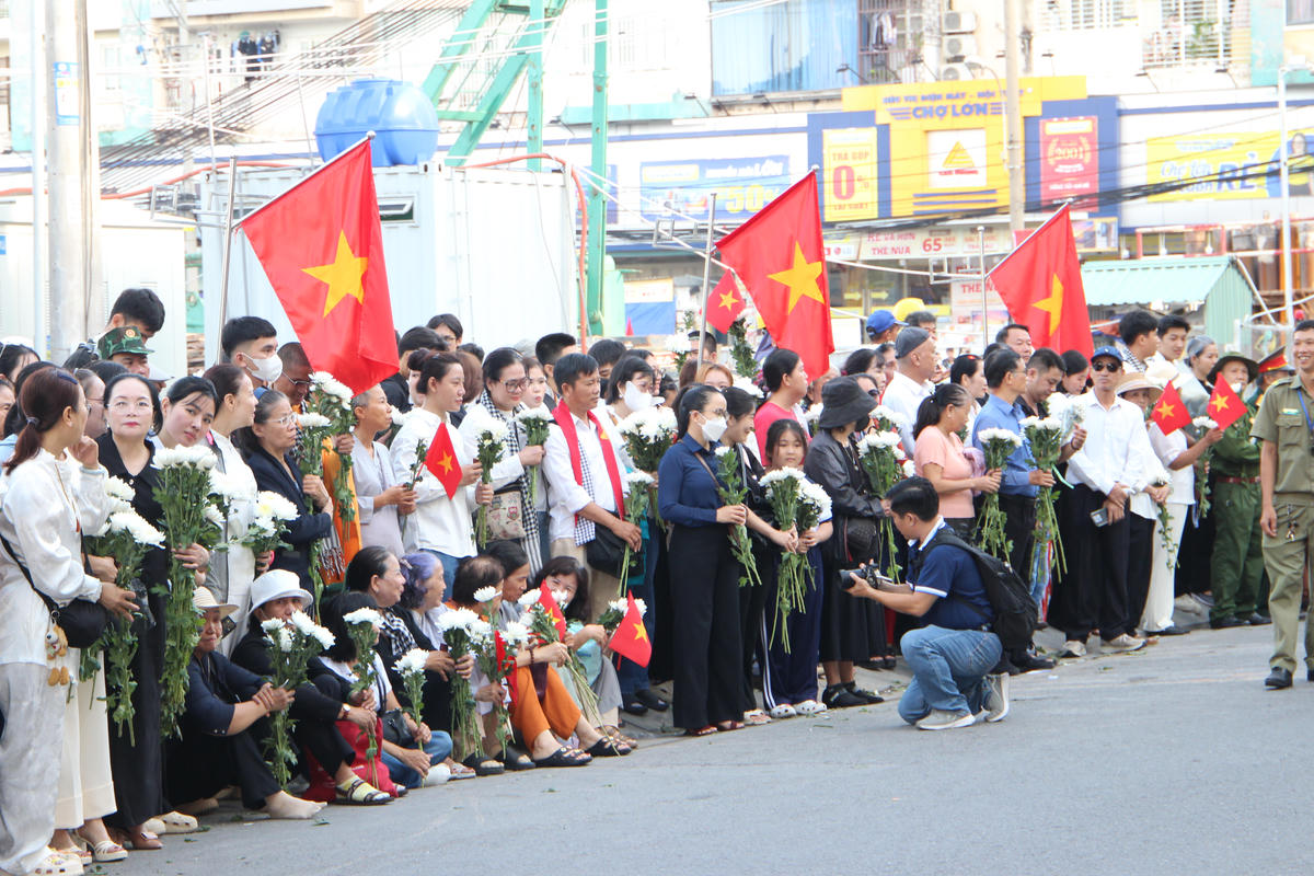Rất đông người dân TPHCM đứng hai bên đường (đoạn vào cổng chính Công viên Lê Thị Riêng) để cầu nguyện và tiễn đưa các anh hùng liệt sĩ về nơi an táng. Ảnh: QĐ.