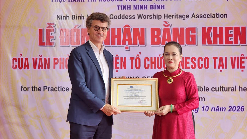 Ông Jonathan Wallace Baker trao tặng bằng khen cho Nghệ nhân Ưu tú Trần Thị Huệ - Thủ nhang Phủ chính Phủ Dầy. Ảnh: Quỳnh Trâm.