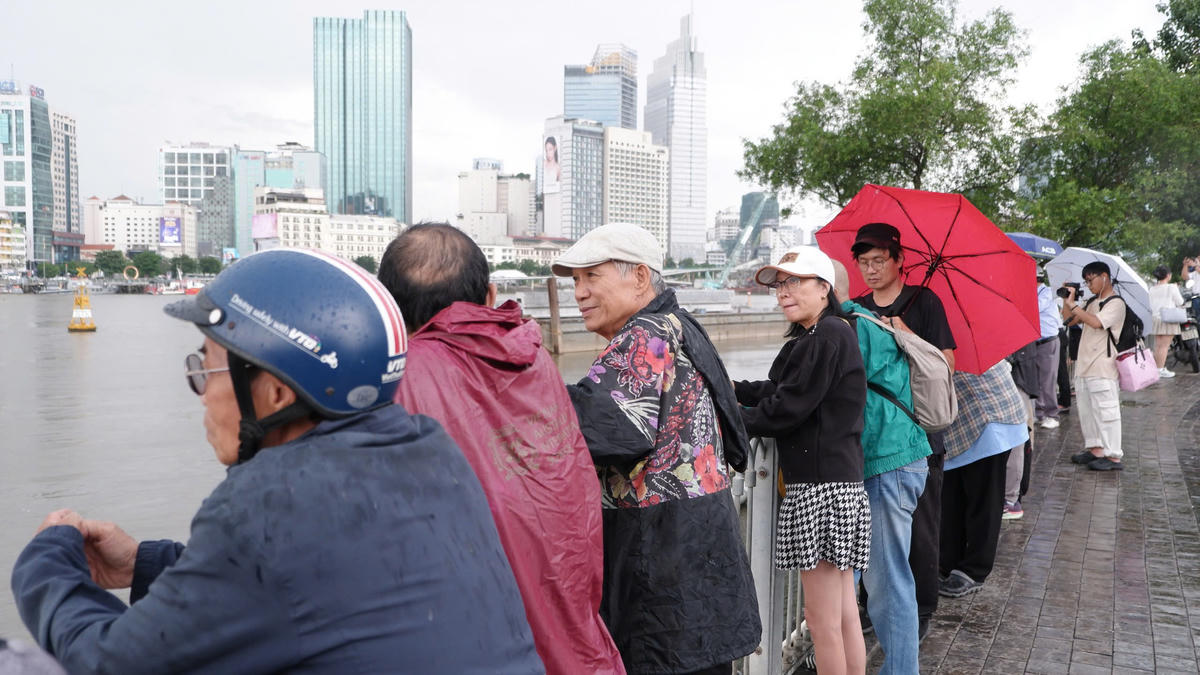 Nhiều người mặc áo mưa, mang dù nhưng vẫn tỏ ra vui vẻ khi nhìn vòm thép. Ảnh: Đ.Xá.