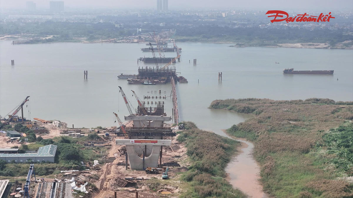 Theo ghi nhận tại công trường giữa tháng 10/2026, các kỹ sư, công nhân được bố trí thành nhiều mũi thi công, tập trung triển khai các hạng mục trụ cầu dưới lòng sông và trên bờ. Máy móc, sà lan hoạt động liên tục để phục vụ vận chuyển vật liệu, thi công cọc khoan nhồi, đổ bê tông trụ và đúc dầm.